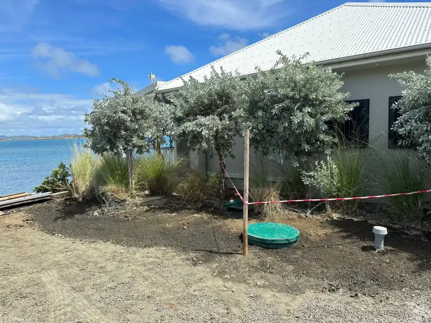 Jardin face à la mer refait après la pose, le couvercle rond de la micro-station WPL Diamond au ras du sol, entouré de gravier